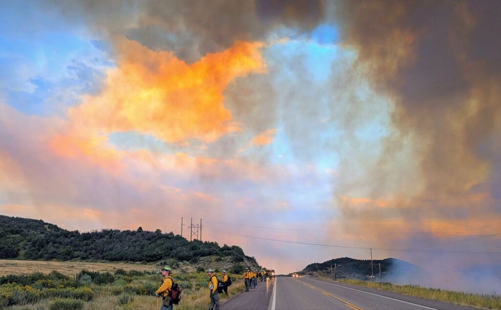 Firefighter line along roadway below evening clouds